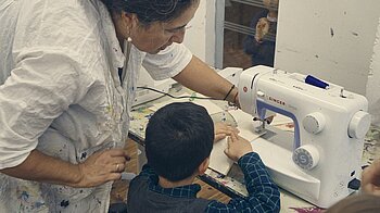 Bild: Junge an Nähmaschine mit kontiki-Dozentin