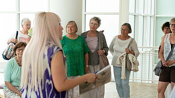 Eine Gruppe Frauen hören bei einer Führung im Stadthaus zu