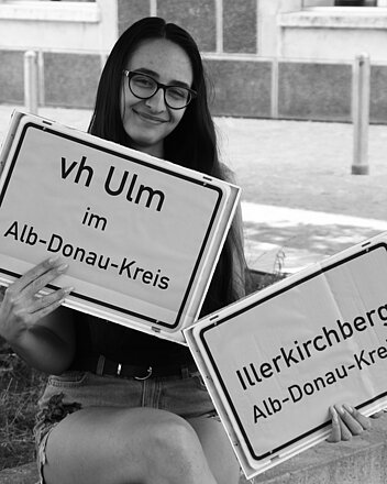 Bild: Frau hält Ortsschild Illerkirchberg und Schild Vh Ulm im Alb-Donau-Kreis