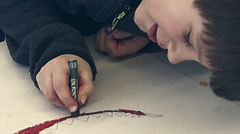 Bild: Liegender Bub mal rot am Boden