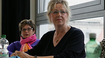 Eine Frau hört gespannt im Unterricht zu