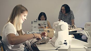 Bild: Drei Frauen sind konzentriert am Nähen