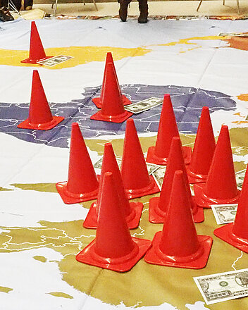 Bild: Weltkarte mit Pylonen und Dollarnoten im Club Orange