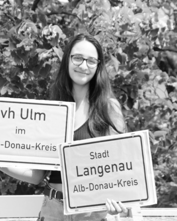 vh Ulm in Langenau Bild: Frau hält Stadtschild Langenau und vh Ulm im Alb-Donau-Kreis