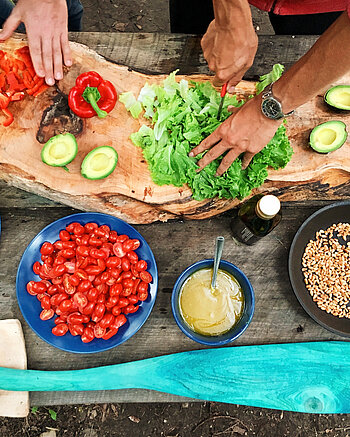 Bild: Zwei Menschen schneiden frisches Gemüse.