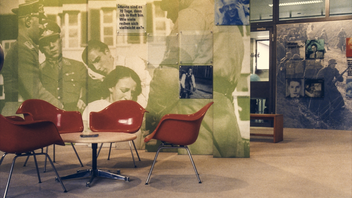 Bild: Orangene Stühle vor einer Wand mit Bild aus dem Nationalsozialismus