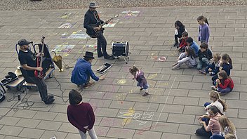 Bild: Kinder sitzen vor Musikband und malen auf dem Pflaster vor dem kontiki