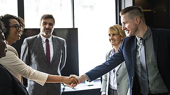 Bild: Zwei Menschen geben sich die Hand.