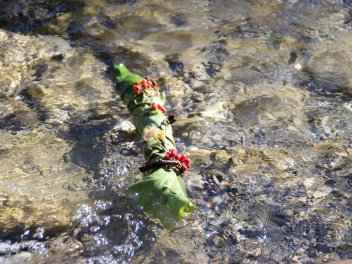 Ein mit Blättern dekorierter Holzstock schwimmt im Wasser