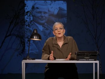 Eine Frau an einem Tisch mit Schreibmaschine und Tischlampe