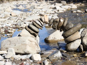 Steine am Wasser, die zusammen einen Bogen bilden